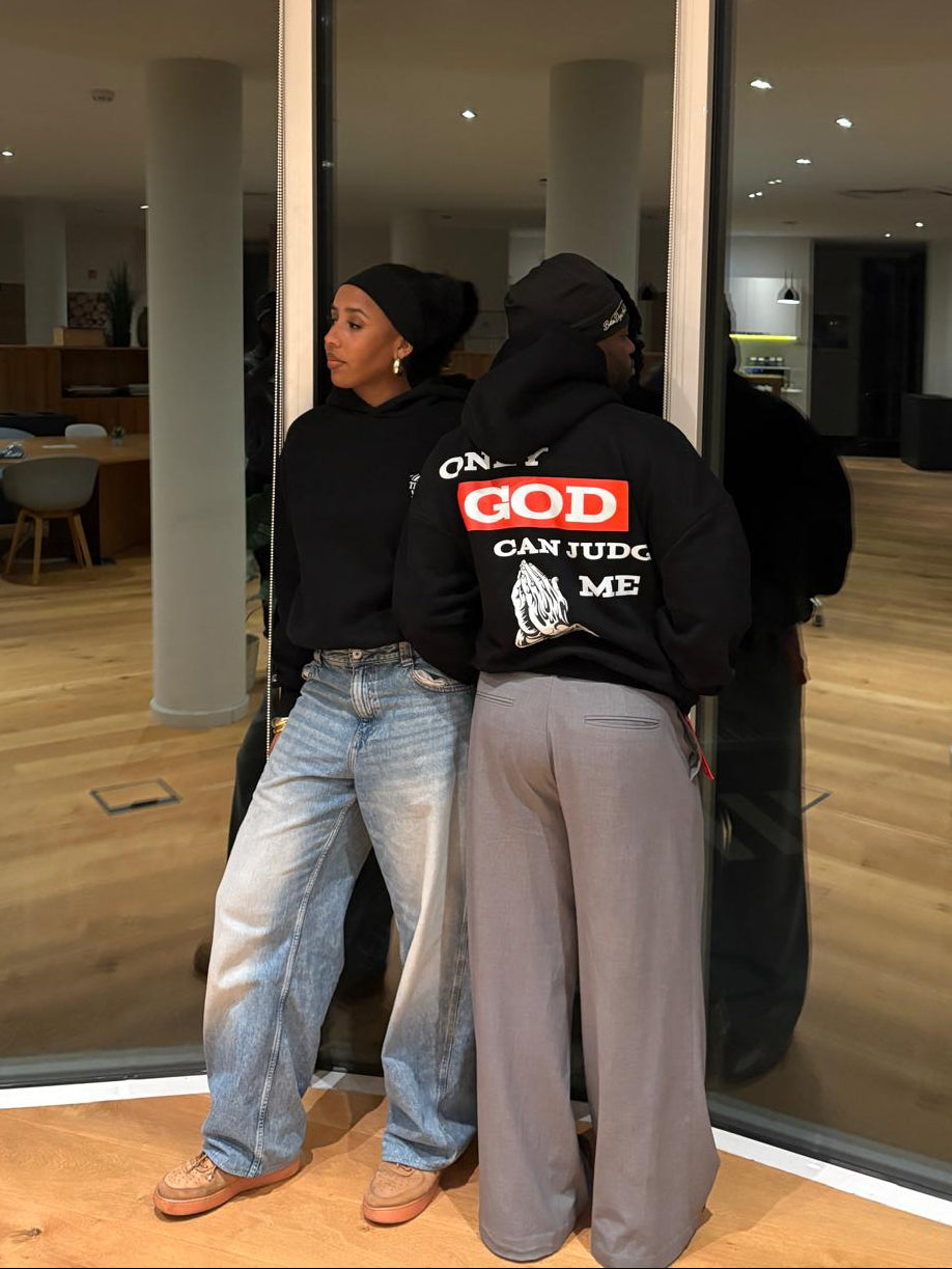 Two people standing close together in a modern indoor setting with large windows.